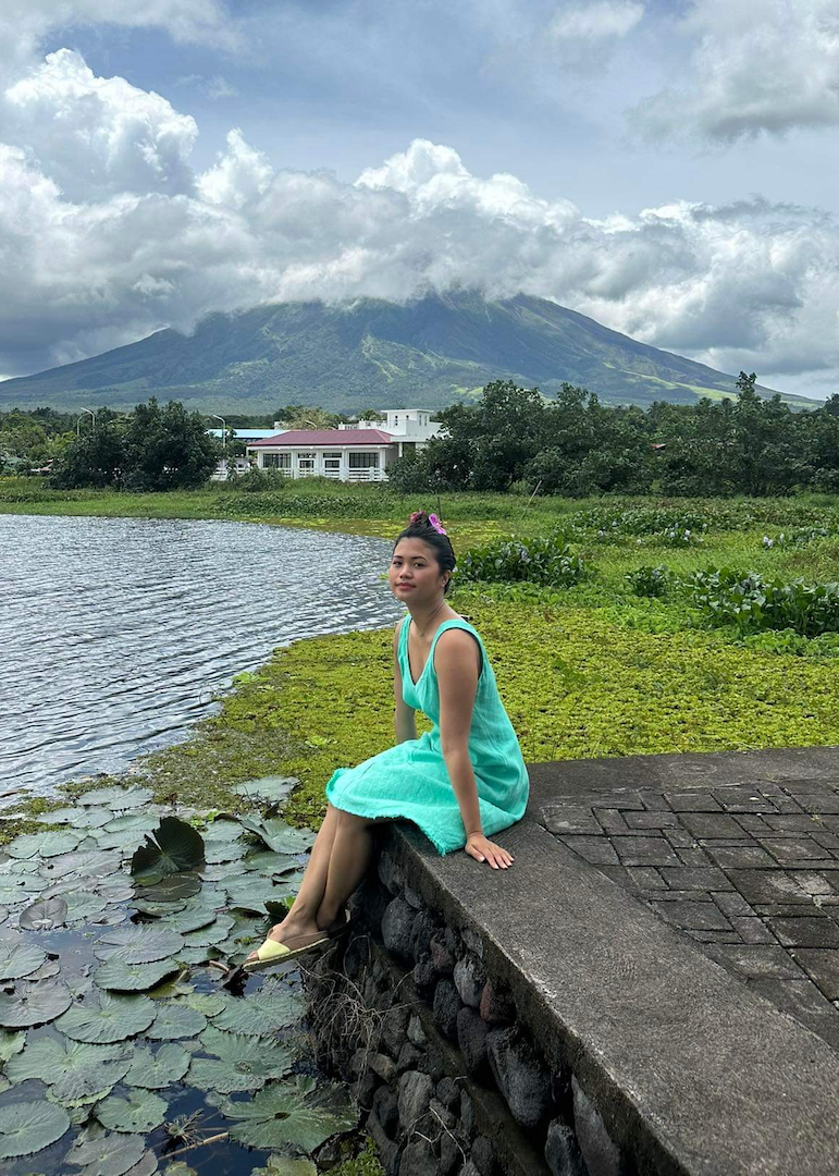 A photo of Graey doing a yoga pose in front of the Mayon volcano.